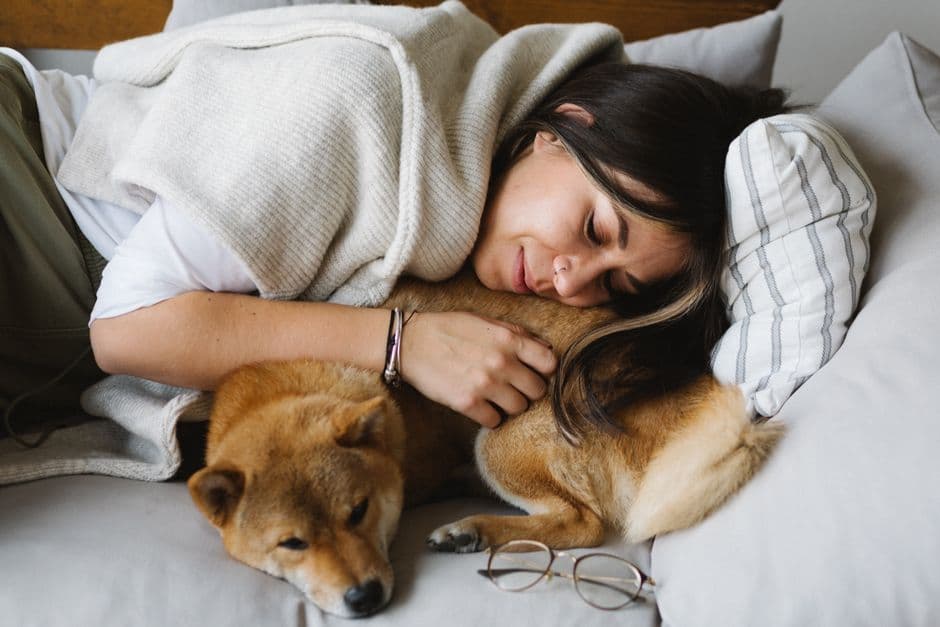 Tutora deitada no sofá abraçada ao seu cão